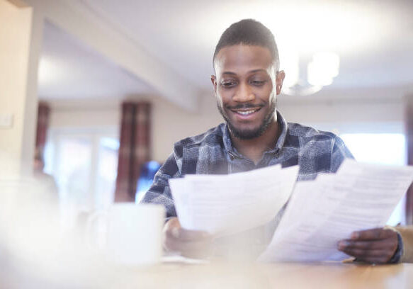 Young black male reading through some paperwork at home