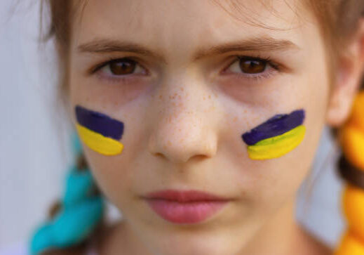 close-up girl's face with yellow-blue national flags of Ukraine painted on her cheeks. concept of Ukrainian patriotism, independence day. sports and fan support.